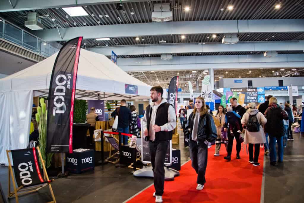 Stánky vystavovatelů a návštěvníci na veletrhu POZNAŃ RUN EXPO 2025 v MTP Poznań Expo – ukázky běžeckého vybavení a doplňků.