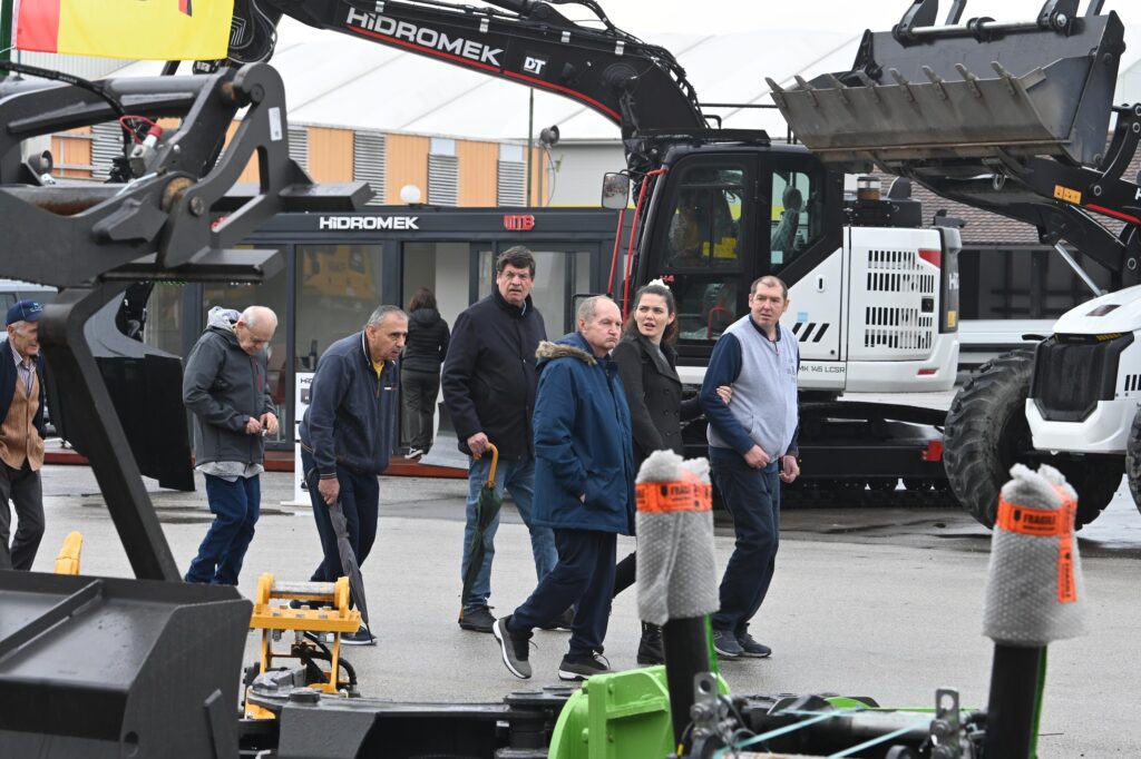 Návštěvníci veletrhu MEGRA si na venkovní ploše prohlížejí vystavené stavební stroje a techniku, včetně bagrů a nakladačů značky Hidromek.