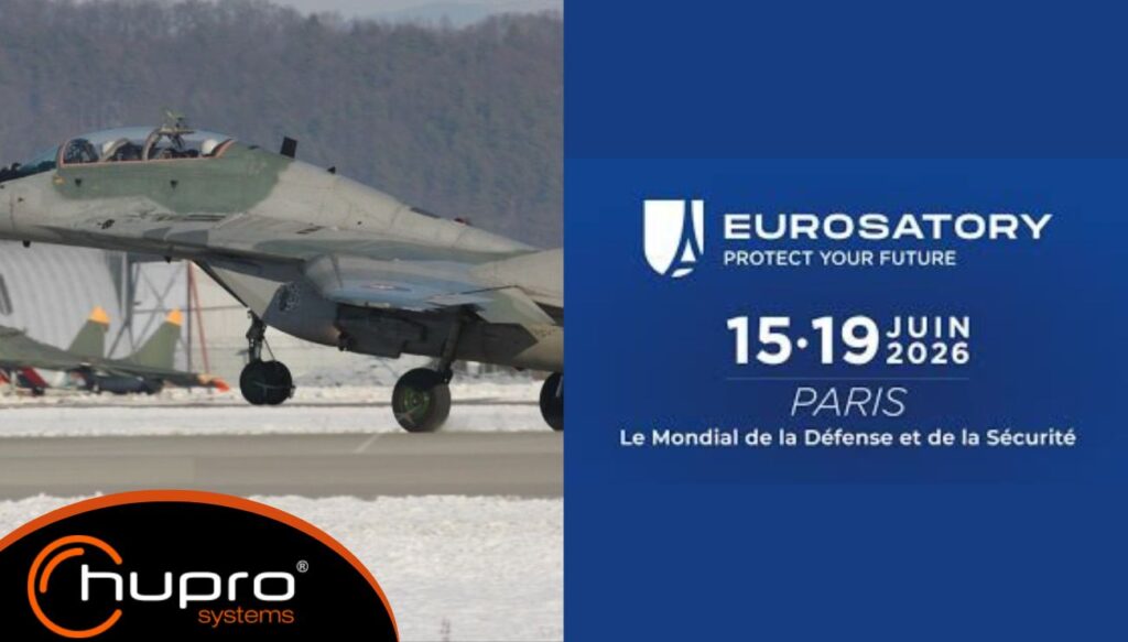 Stíhačka a oficiální vizuál Eurosatory 2026 v Paříži s logem HUPRO SYSTEMS SE, výrobce obloukových ocelových hal.