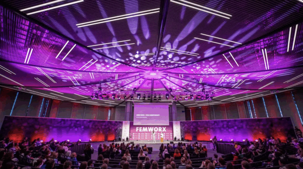 Sál FEMWORX na Hannover Messe během prezentace, osvětlený fialovou scénografií a zaplněný účastnicemi konference.