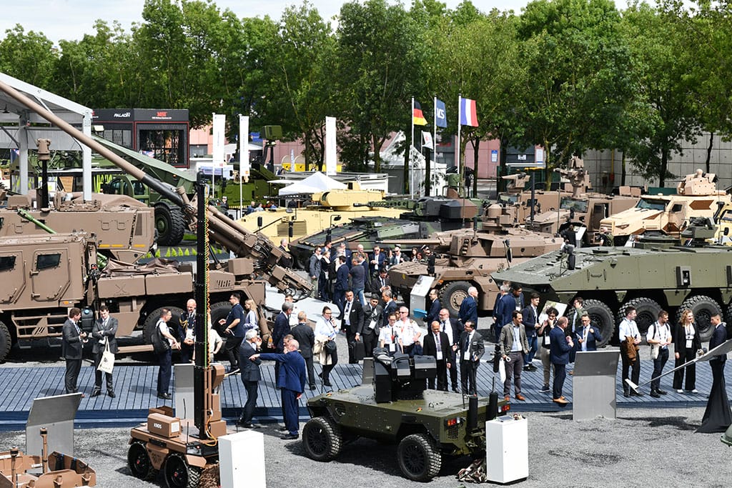 Ukázka pozemní vojenské techniky a návštěvníků na veletrhu Eurosatory s vystavenými obrněnými vozidly a systémy obrany.