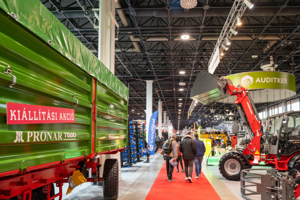 Návštěvníci procházejí expozicí zemědělské techniky na AGROMASH Expo, se stroji Pronar, nakladačem Weidemann a stánkem Auditker.